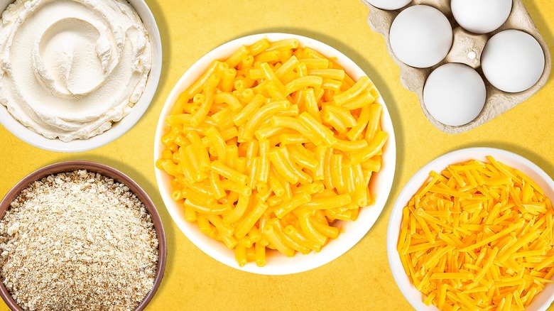 A bowl of breadcrumbs, cream cheese, eggs, cheddar cheese, and mac and cheese