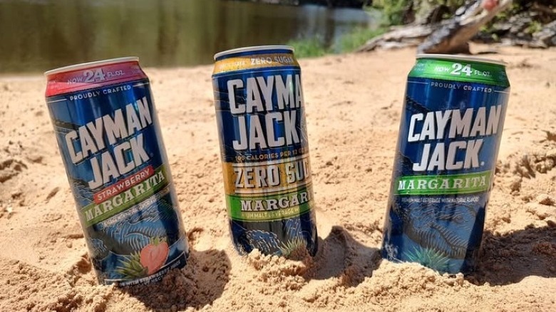 Canned Cayman Jack Zero Sugar margaritas sit in the sand