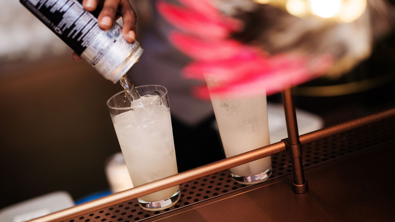 A bartender pours a canned cocktail into a glass