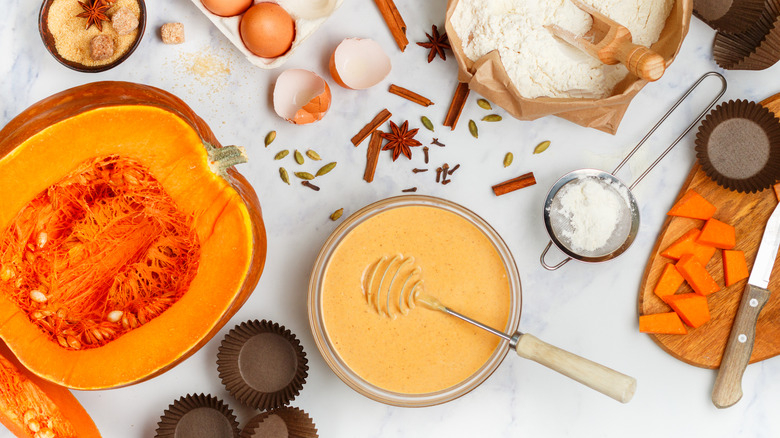 A top view of ingredients for pumpkin muffins on a white background