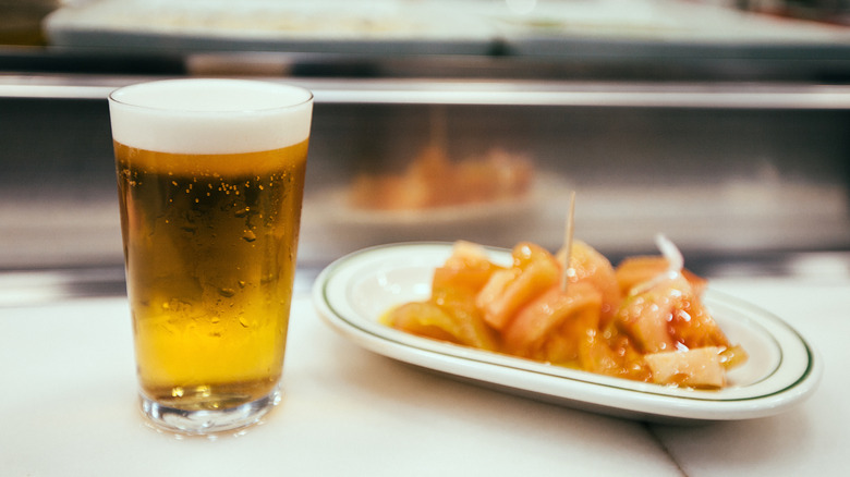 Glass of foamy beer and plate of shrimp