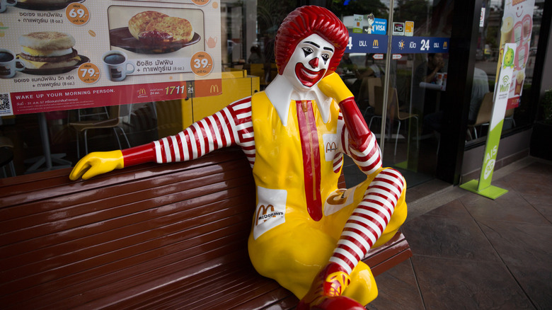 statue of Ronald McDonald sitting on brown bench