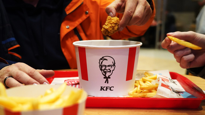 Customer taking piece of chicken from KFC bucket