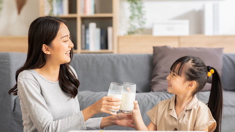 Mother and daughter toasting milk
