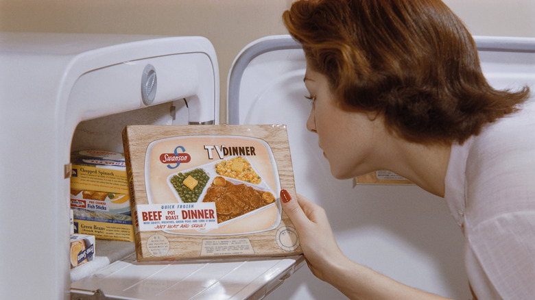 A woman taking a TV dinner out if a freezer in the 1960s.