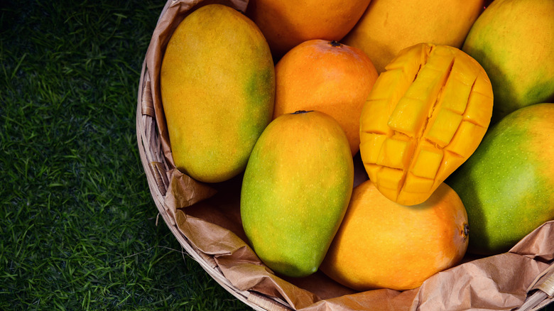 Whole and halved mangos in basket