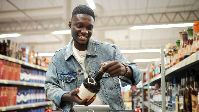 A man holding a bottle in a grocery store aisle