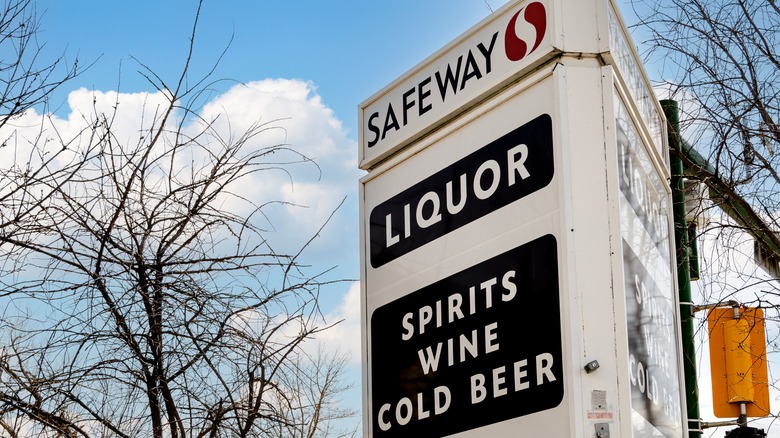Safeway liquor signage next to a stoplight and trees