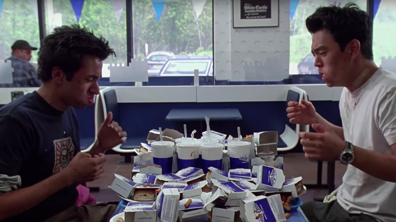 Harold and Kumar eat White Castle burgers at a table