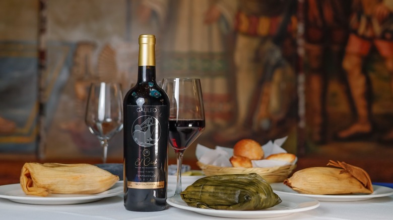 A bottle of El Cielo Galileo on a table with plates of tamales