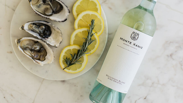 A bottle of Monte Xanic Sauvignon Blanc Viña Kristel next to a plate of oysters with lemon
