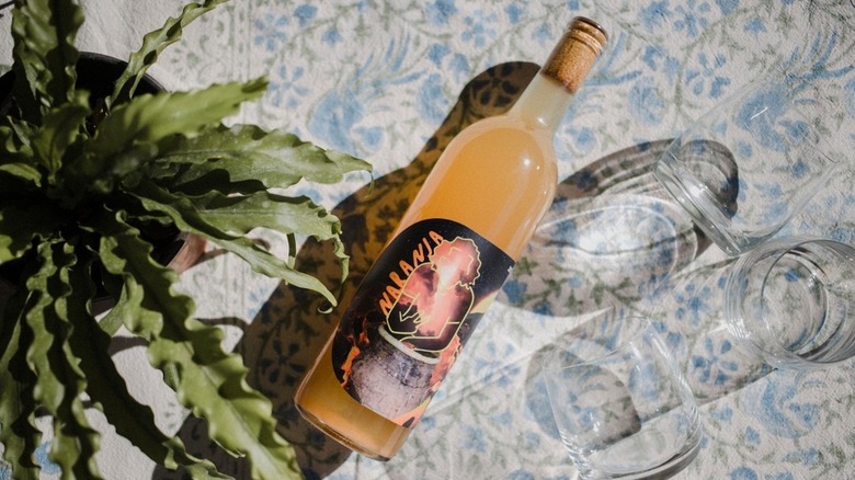 A bottle of Octagono Naranja on a table with glasses