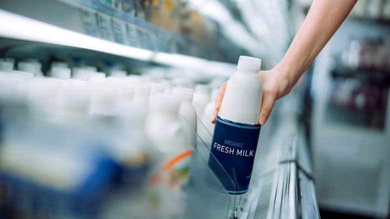 A woman grabbing organic fresh milk at the supermarket
