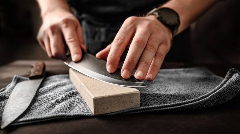 man sharpening knife on counter