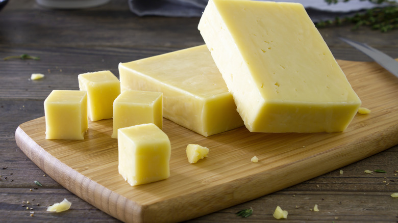 Cheese cubes and blocks are arranged on a cutting board.