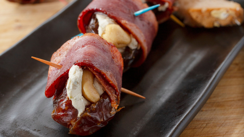 Devils on horseback, which are bacon-wrapped dates, photographed in close-up.