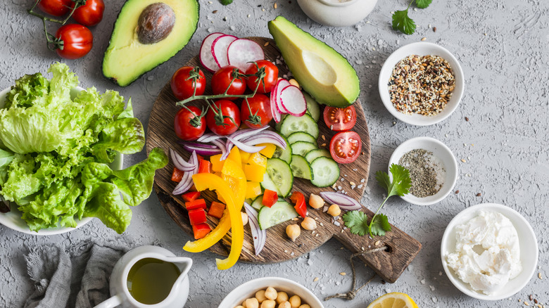 Several produce varieties like tomatoes, cucumbers, and avocados are arranged on a tray.