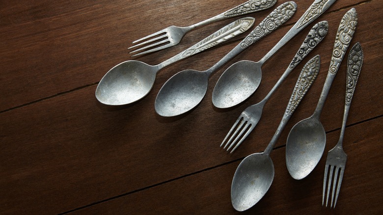 Assortment of antique forks and spoons on brown wooden table