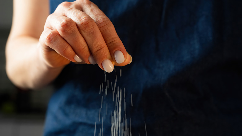 Woman sprinkling ingredients onto food
