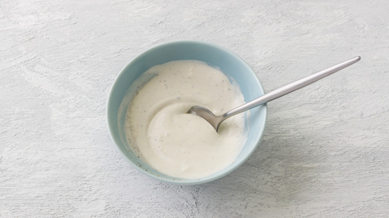 small blue bowl filled with white dressing on gray surface