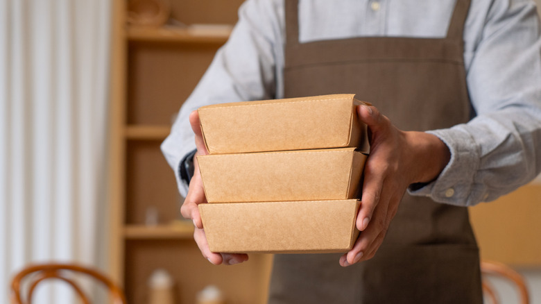 Man holding stack of takeout boxes