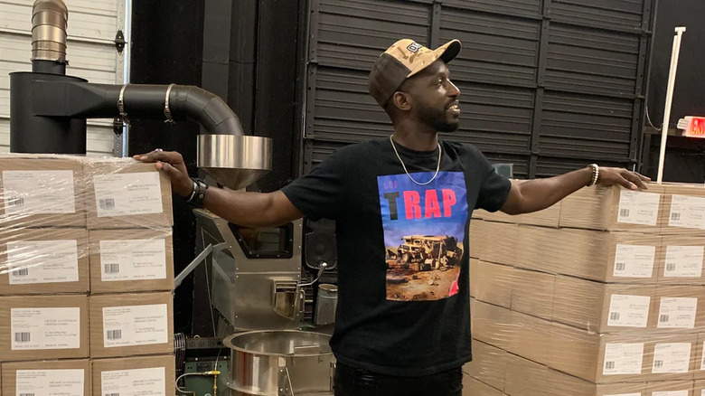 Man in roastery space between palettes of packaged coffee