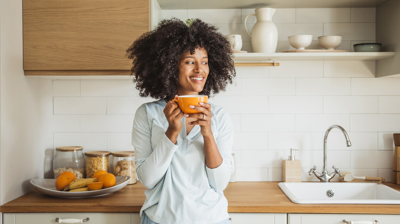 Black woman drinking coffee in kitchen