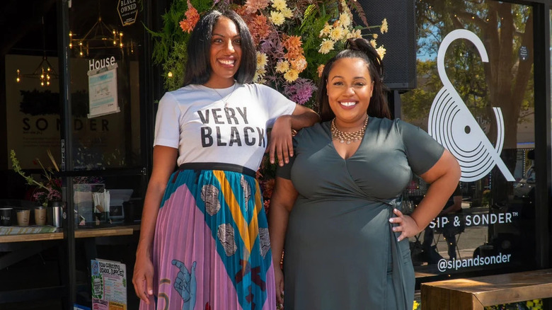 Two women standing outside of the Sip & Sonder storefront