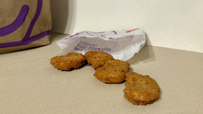 Four chicken nuggets on a tan surface