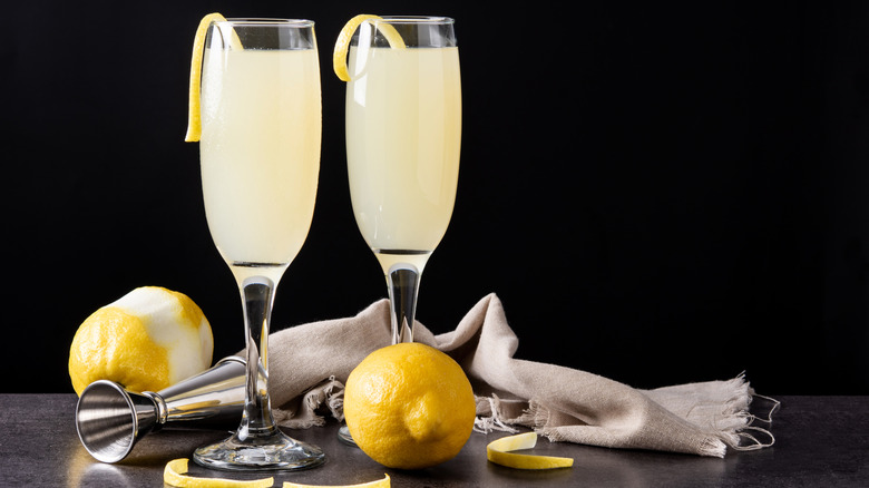 Two French 75 cocktails on a bar with lemons