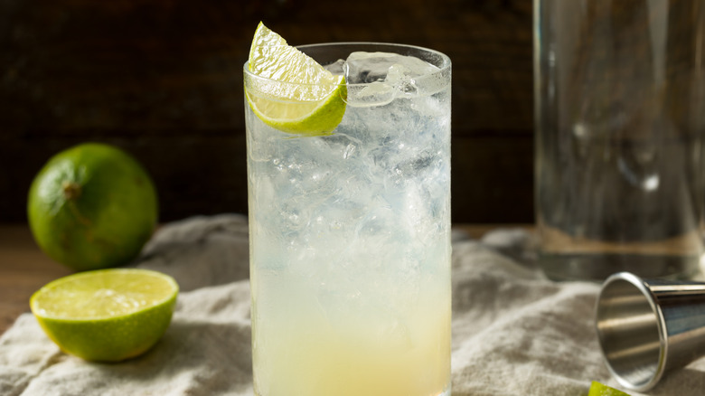 A Gin Rickey cocktail on a table with limes