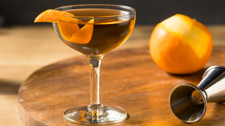 A cocktail in a coupe glass with an orange twist