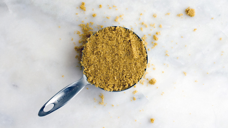 Cup of packed brown sugar on a marble surface