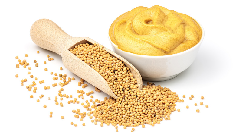 A bowl of mustard next to mustard seeds