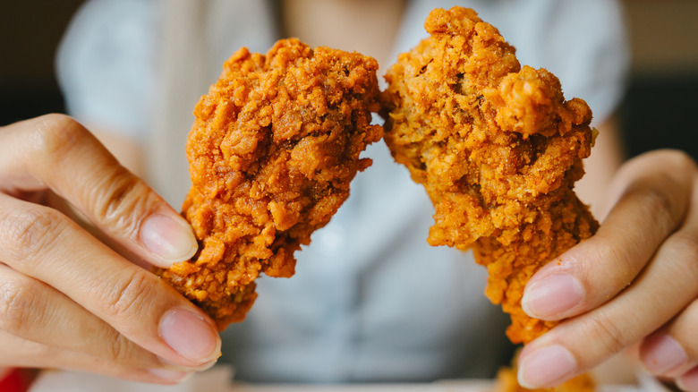Person holding two fried chicken wings