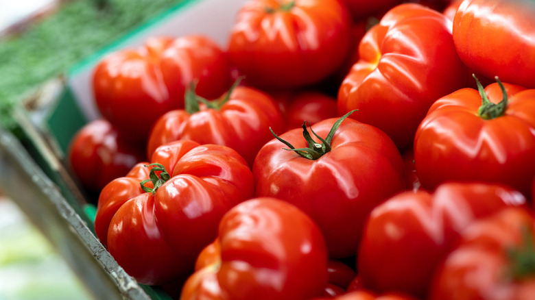 A close-up of bright red, shiny tomatoes piled on top of each other
