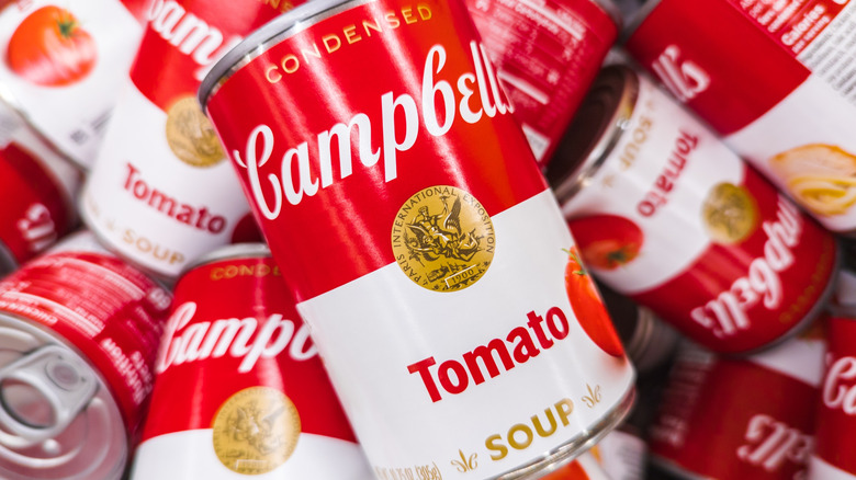 A pile of Campbell's Soup cans with tomato-flavored variety in forefront