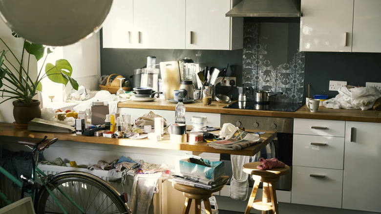 A small kitchen with clutter on the counter tops