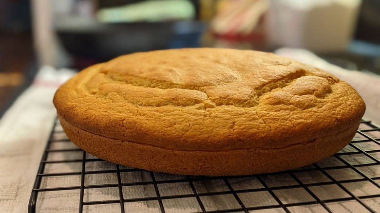 A round loaf of cornbread cooling on a wire rack