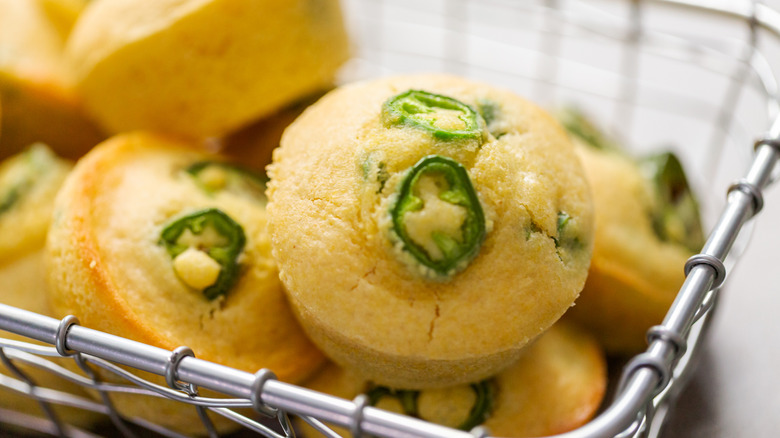 Cornbread muffins with jalapeños in the batter in a wire basket