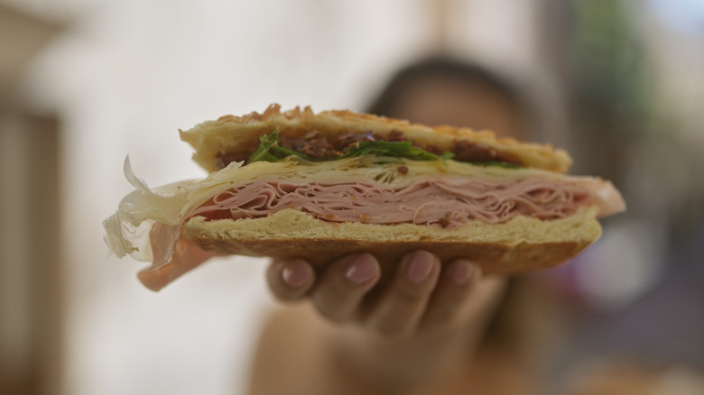 A blurred woman in the background holding out a puccia sandwich
