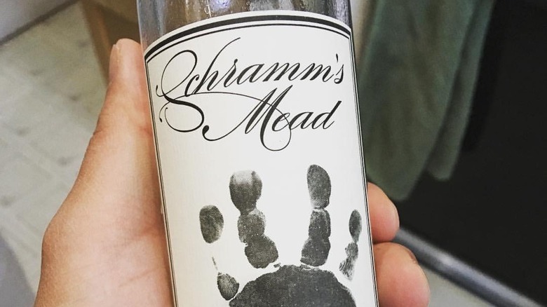 A hand is holding a bottle of Schramm's Loganberry Mead.