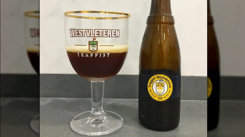 A glass of Westveleteren sits next to a bottle on a shelf.