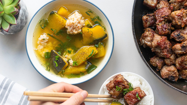 A bowl of canh bí đỏ nấu thịt băm next to a meat dish