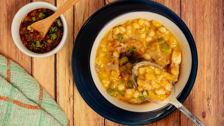 A bowl of locro de zapallo with chili oil on the side