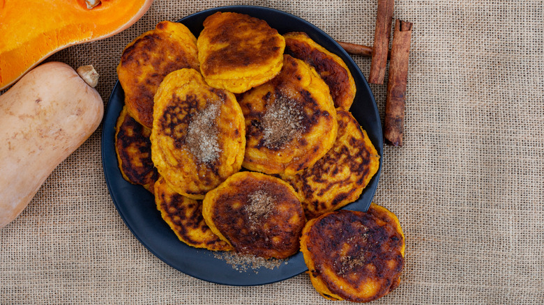 A plate of pampoenkoekies with butternut squash and cinnamon sticks nearby