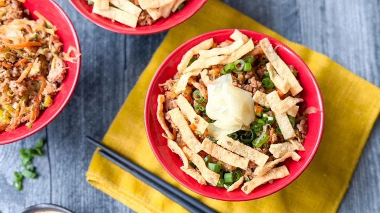 a red bowl with ground pork, wontons, scallions, and other ingredients from a pork egg roll