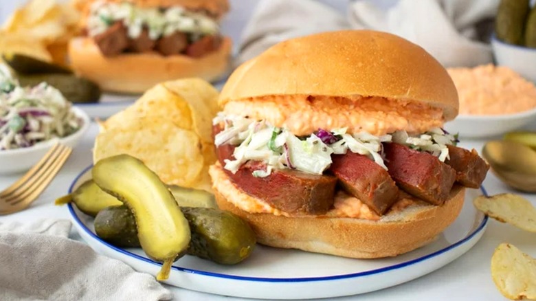a sandwich filled with meatloaf, pimento cheese, and coleslaw on a plate