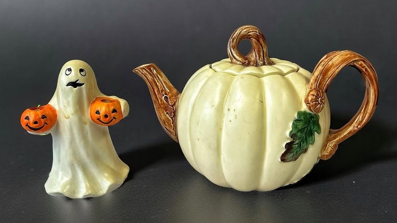 Vintage pumpkin teapot next to ceramic ghost in front of gray background