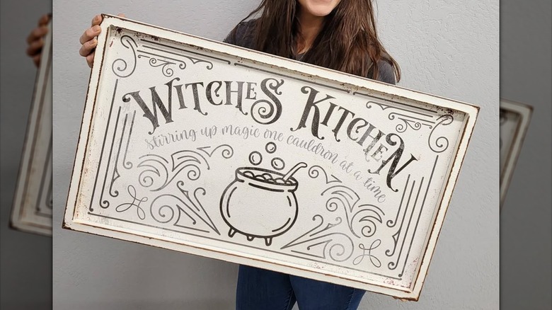 Person holding a rustic witches' kitchen sign